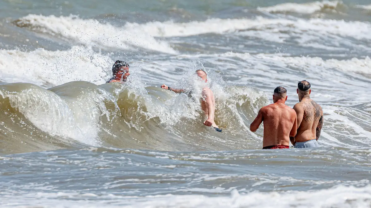 10.06.2023, Schleswig-Holstein, Timmendorfer Strand: Vier Männer baden in starker Brandung vor Timmendorfer Strand. Foto: Markus Scholz/dpa +++ dpa-Bildfunk +++
