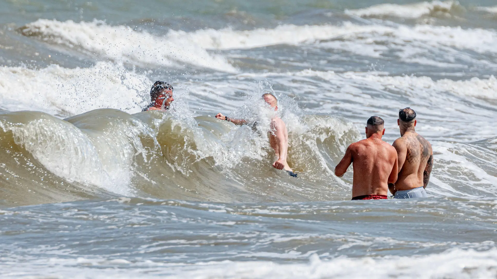 10.06.2023, Schleswig-Holstein, Timmendorfer Strand: Vier Männer baden in starker Brandung vor Timmendorfer Strand. Foto: Markus Scholz/dpa +++ dpa-Bildfunk +++
