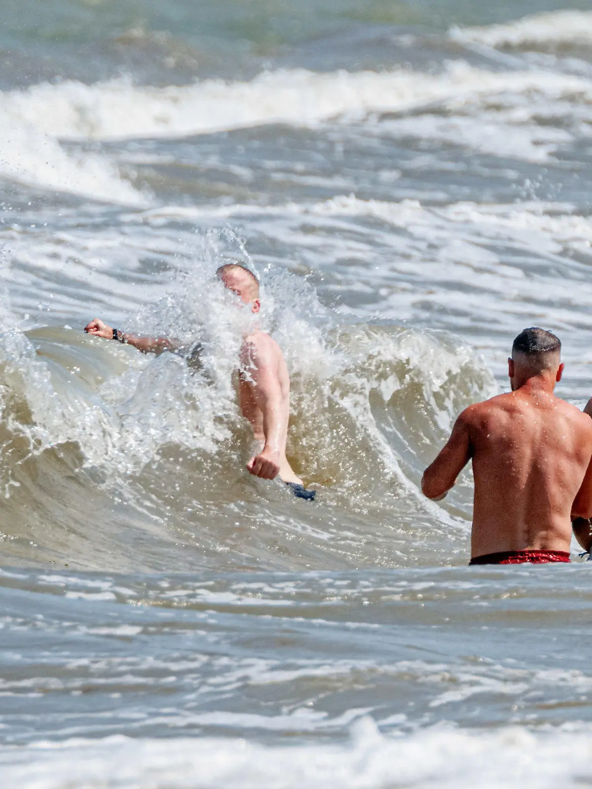 10.06.2023, Schleswig-Holstein, Timmendorfer Strand: Vier Männer baden in starker Brandung vor Timmendorfer Strand. Foto: Markus Scholz/dpa +++ dpa-Bildfunk +++
