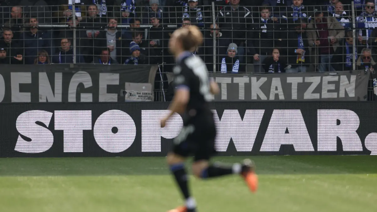 02.04.2022, Nordrhein-Westfalen, Bielefeld: Fußball: Bundesliga, Arminia Bielefeld - VfB Stuttgart, 28. Spieltag in der Schüco-Arena. "Stop War" steht auf einer Werbebande. Foto: Friso Gentsch/dpa - WICHTIGER HINWEIS: Gemäß den Vorgaben der DFL Deutsche Fußball Liga bzw. des DFB Deutscher Fußball-Bund ist es untersagt, in dem Stadion und/oder vom Spiel angefertigte Fotoaufnahmen in Form von Sequenzbildern und/oder videoähnlichen Fotostrecken zu verwerten bzw. verwerten zu lassen. +++ dpa-Bildfunk +++
