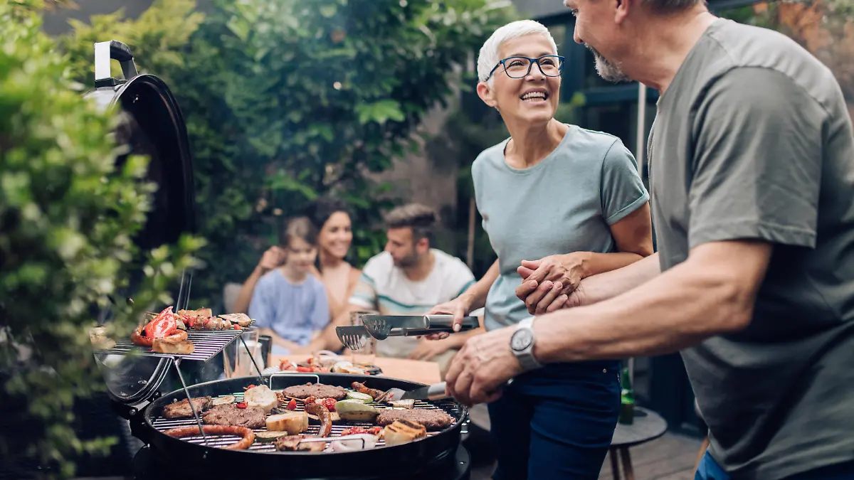 Senior couple preparing barbecue for the whole family at the backyard.
