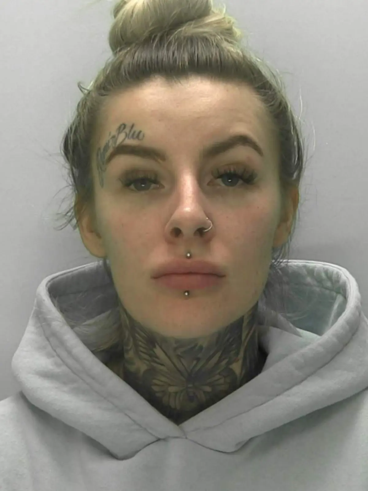Eine Frau mit blonden Haaren und Gesichtstattoos.