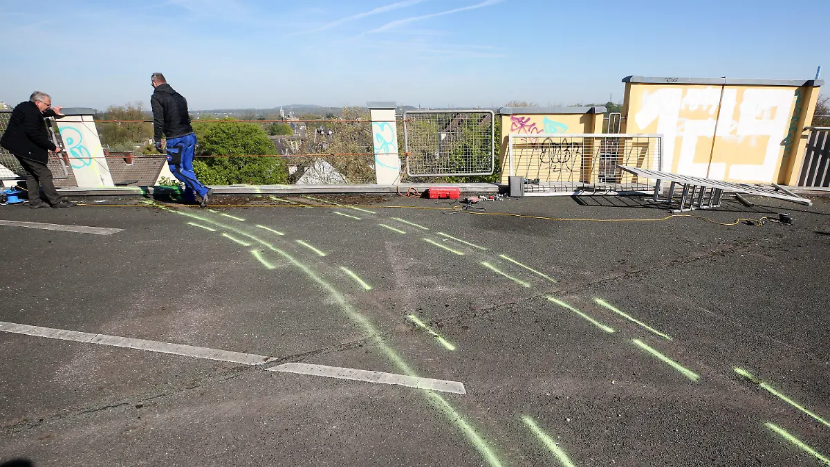 19.04.2022, Nordrhein-Westfalen, Essen: Zwei Arbeiter bereiten die Reparatur der Stelle am Parkhausdach vor, wo zwei jungen Männer mit ihrem Auto in den Tot stürtzten. Es steht nach Angaben der Polizei aus der Nacht der Verdacht im Raum, dass der Wagen auf dem Parkdeck für Fahrmanöver genutzt wurde - und deshalb durch ein Geländer schoss. Foto: Roland Weihrauch/dpa +++ dpa-Bildfunk +++