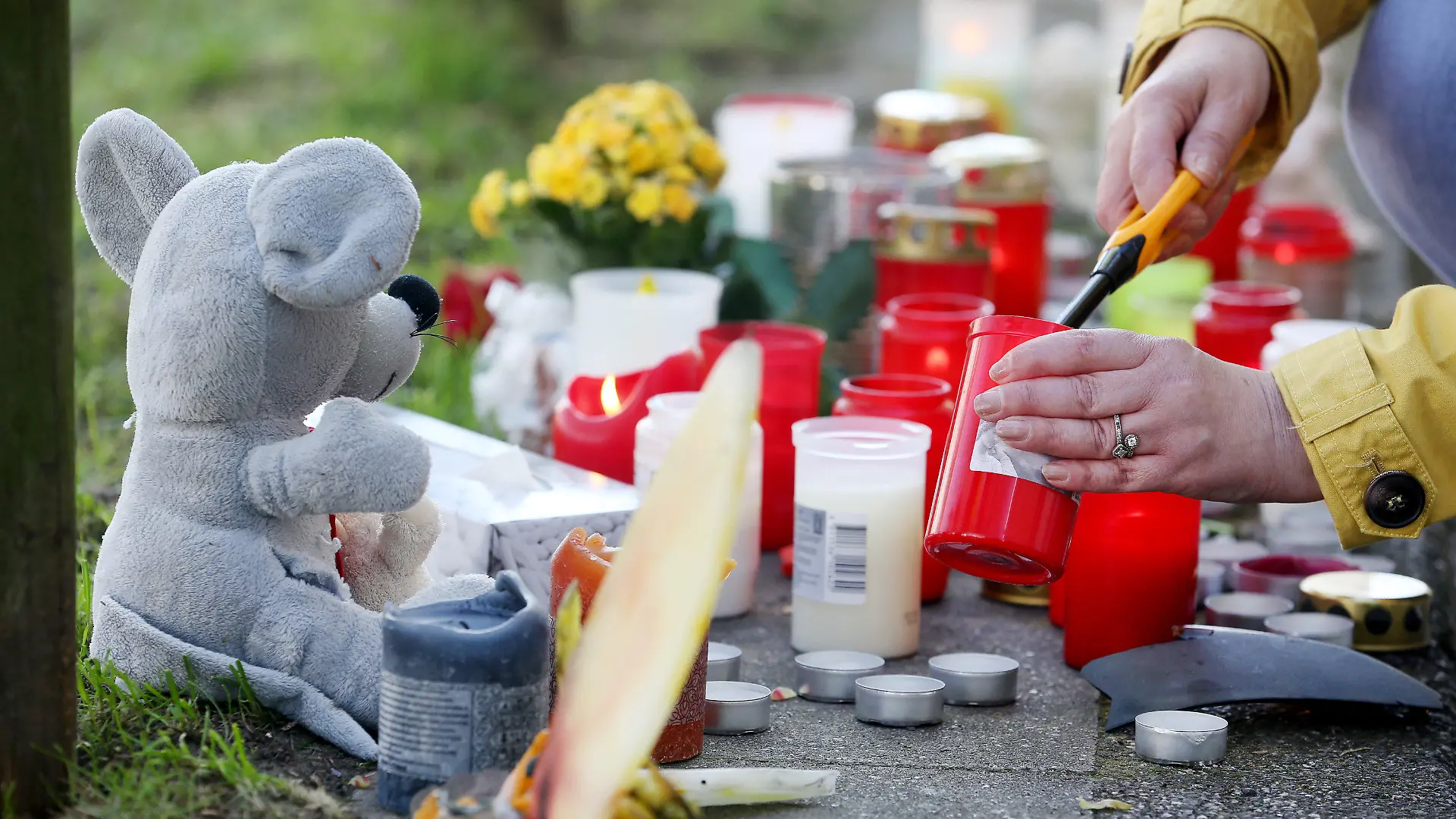 19.04.2022, Nordrhein-Westfalen, Essen: Eine Anwohnerin zündet am Parkhaus, von dessen Dach ein Auto mit zwei jungen Männern gestürzt war, eine Kerze an. Es steht nach Angaben der Polizei aus der Nacht der Verdacht im Raum, dass der Wagen auf dem Parkdeck für Fahrmanöver genutzt wurde - und deshalb durch ein Geländer schoss. Foto: Roland Weihrauch/dpa +++ dpa-Bildfunk +++