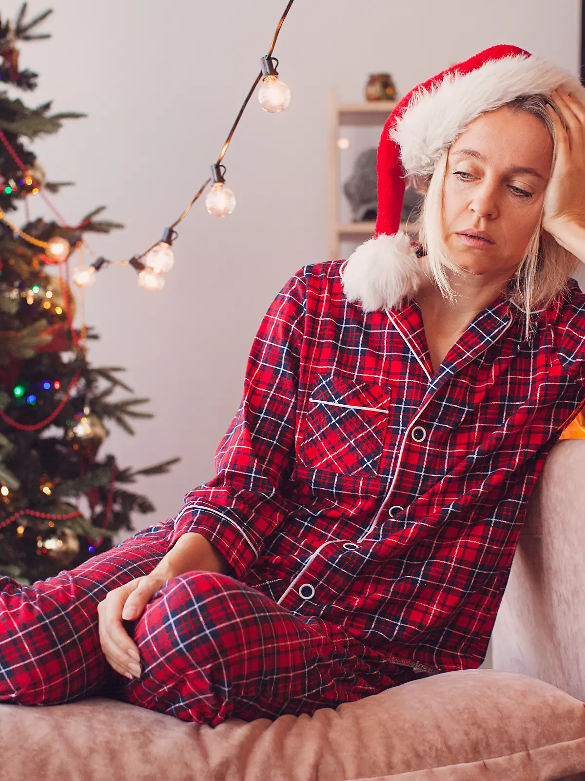 Frau sitzt mit Kater vor dem Weihnachtsbaum.