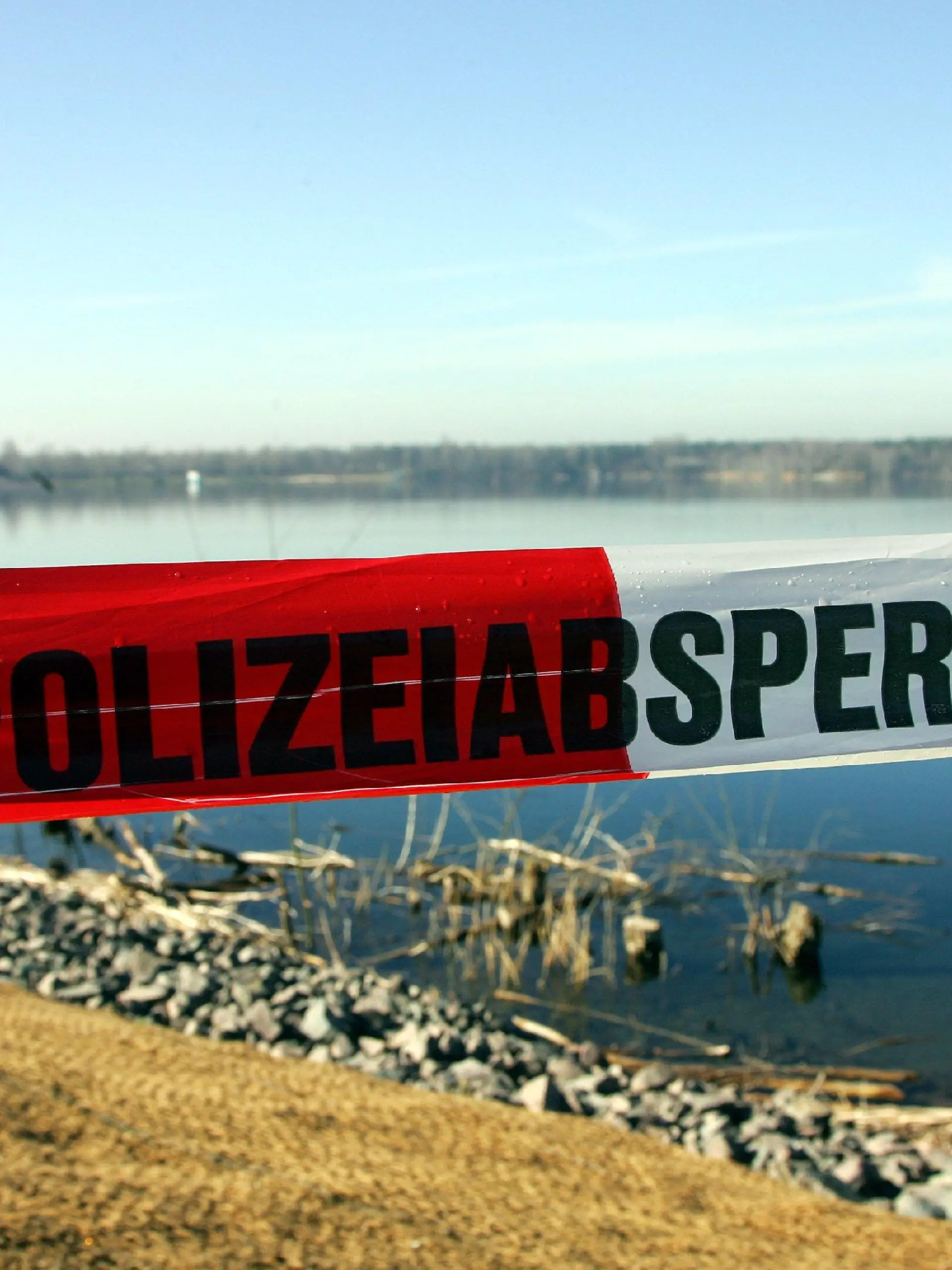 Mit einem rot-weißen Band hat die Polizei am Montag (12.03.2007) eine Stelle am Sandersdorfer See nahe Bitterfeld abgesperrt, an der am Wochenende eine Babyleiche entdeckt worden war. Das Neugeborene lag in einem blauen Plastiksack in der Uferzone, wie die Staatsanwaltschaft Dessau mitteilte. Es handele sich um ein Mädchen, dessen Nabelschnur nicht abgetrennt worden war. Das tote Mädchen ist nach Angaben der Staatsanwaltschaft in der Nacht zum Montag am Institut für Rechtsmedizin Halle untersucht worden. Dabei stellte sich heraus, dass das Kind nach der Geburt kurze Zeit gelebt hatte. Es ist das zweite tote Baby, das innerhalb weniger Tage in Sachsen-Anhalt gefunden wurde. Foto: Arno Burgi dpa/lah (zu dpa 0167 vom 12.03.2007) +++(c) dpa - Bildfunk+++