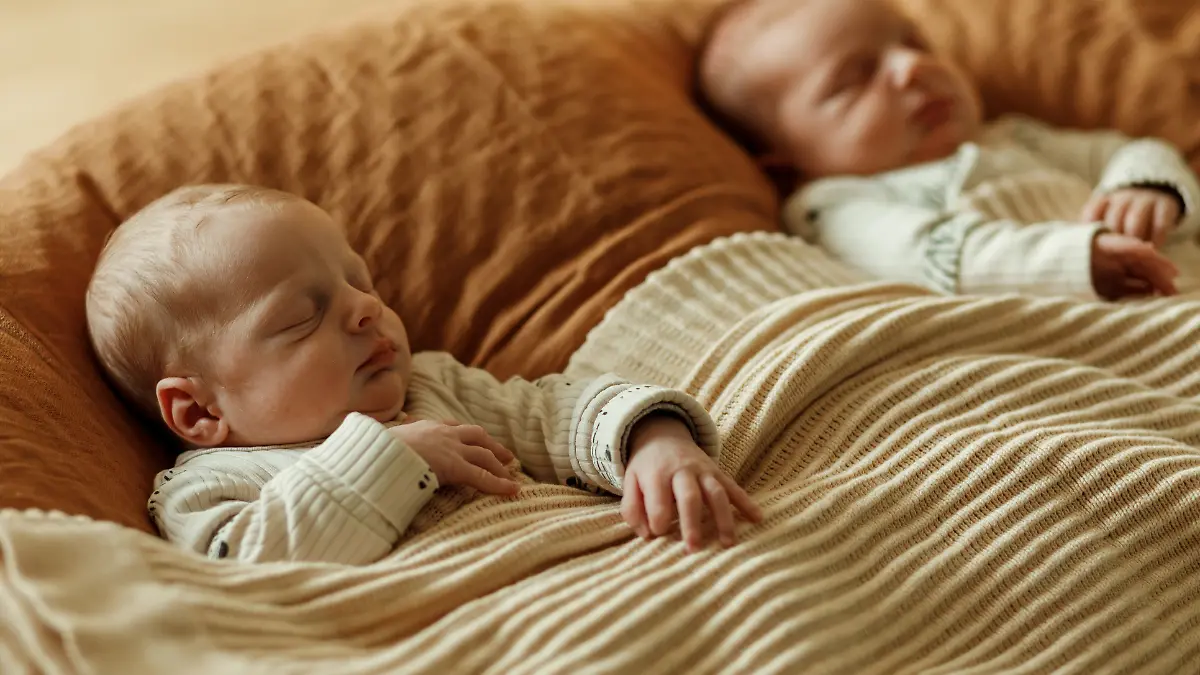 Zwillingsbabys liegen nebeneinander im Bett.