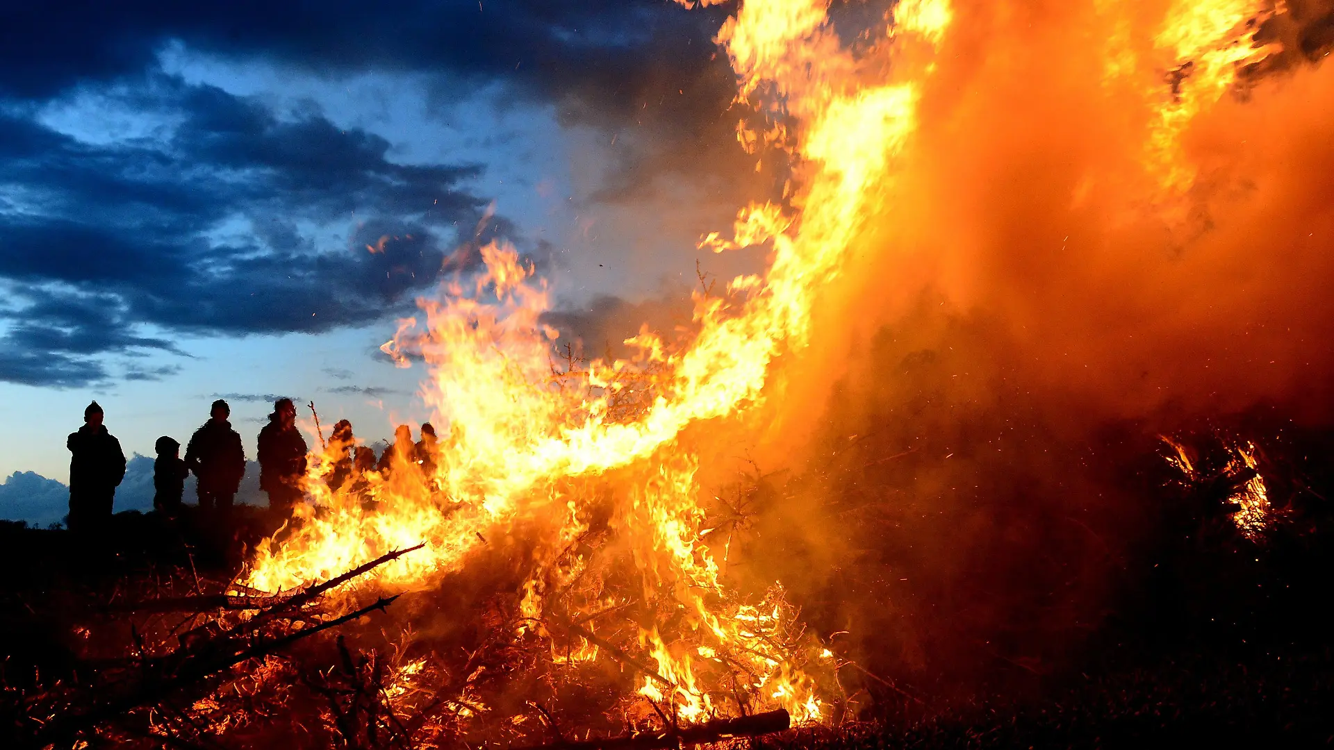 ARCHIV - 15.04.2017, Niedersachsen, Wartjenstedt: Menschen stehen um ein traditionelles Osterfeuer. Vor Corona war das Osterfeuer in vielen Städten und Gemeinden ein fester Bestandteil des Osterwochenendes. Coronabedingt musste sie ausfallen. In diesem Jahr geht's wieder los. (zu dpa "Das Flackern geht los: Osterfeuer wieder möglich") Foto: Maurizio Gambarini/dpa +++ dpa-Bildfunk +++