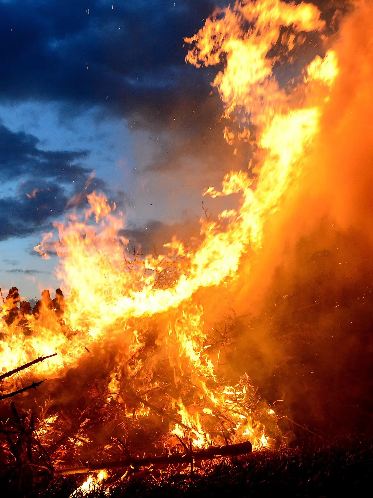 ARCHIV - 15.04.2017, Niedersachsen, Wartjenstedt: Menschen stehen um ein traditionelles Osterfeuer. Vor Corona war das Osterfeuer in vielen Städten und Gemeinden ein fester Bestandteil des Osterwochenendes. Coronabedingt musste sie ausfallen. In diesem Jahr geht's wieder los. (zu dpa "Das Flackern geht los: Osterfeuer wieder möglich") Foto: Maurizio Gambarini/dpa +++ dpa-Bildfunk +++