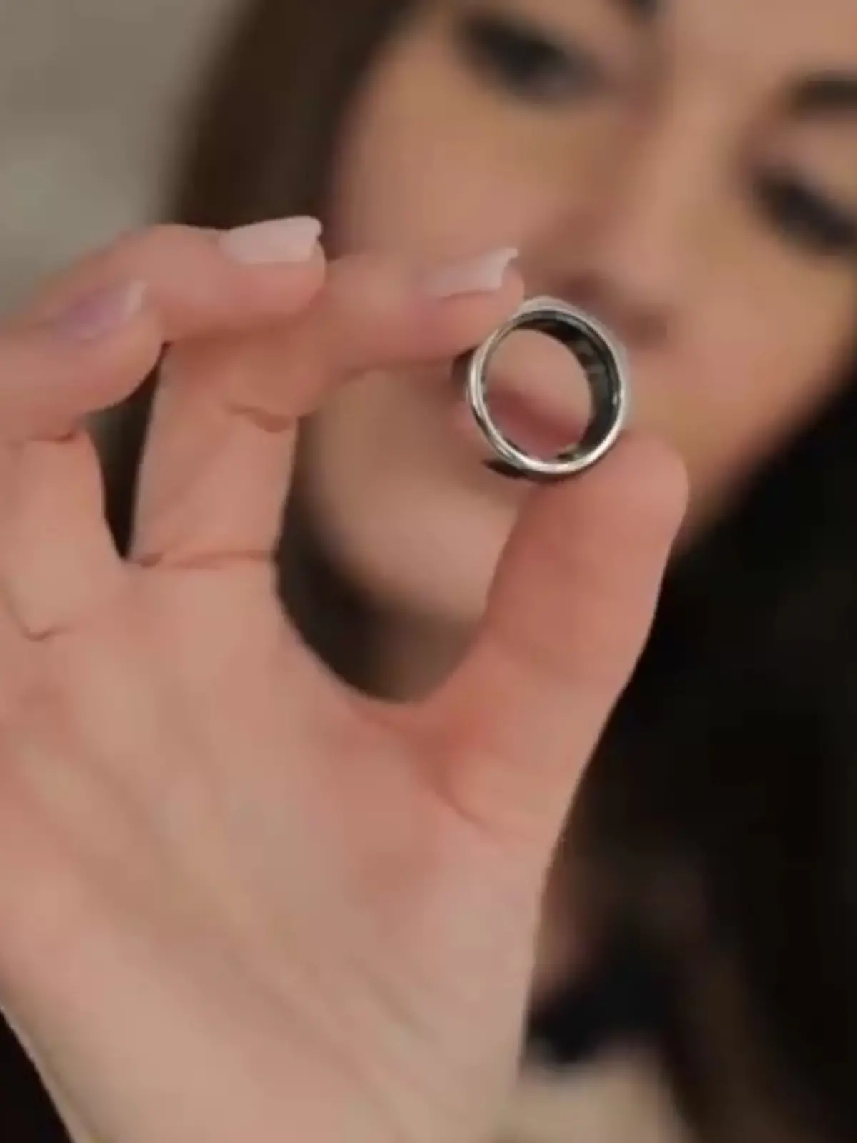 Eine Frau hält einen Health Tracking Ring in die Kamera.