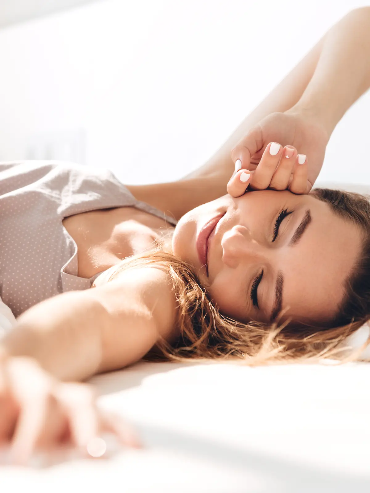 Frau liegt mit geschlossenen Augen im Bett.