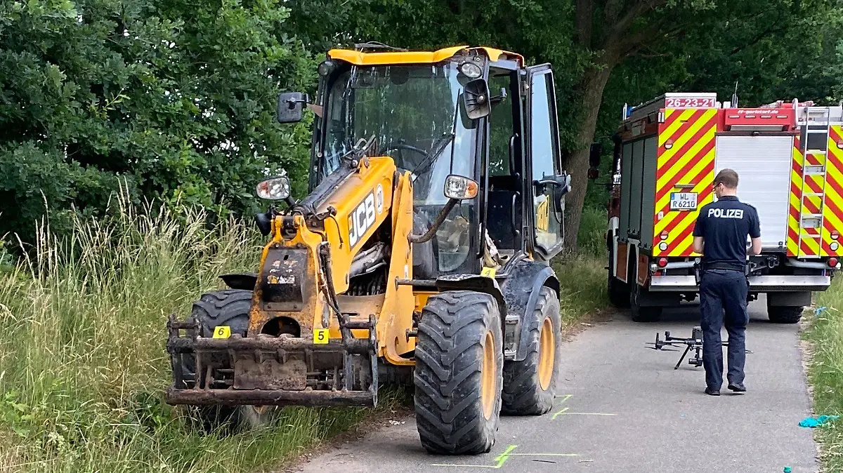 HANDOUT - 24.06.2023, Niedersachsen, Toppenstedt: Polizeibeamte stehen neben einem Bagger nach einem Unfall auf einem Feldweg. Bei einem Unfall während einer Ausflugsfahrt mit einem Bagger sind im Landkreis Harburg ein Kind und ein Erwachsener gestorben. Zehn weitere Kinder wurden nach Feuerwehrangaben am Samstagabend zum Teil schwer verletzt. Foto: Polizei Harburg/dpa - ACHTUNG: Nur zur redaktionellen Verwendung im Zusammenhang mit der aktuellen Berichterstattung und nur mit vollständiger Nennung des vorstehenden Credits +++ dpa-Bildfunk +++