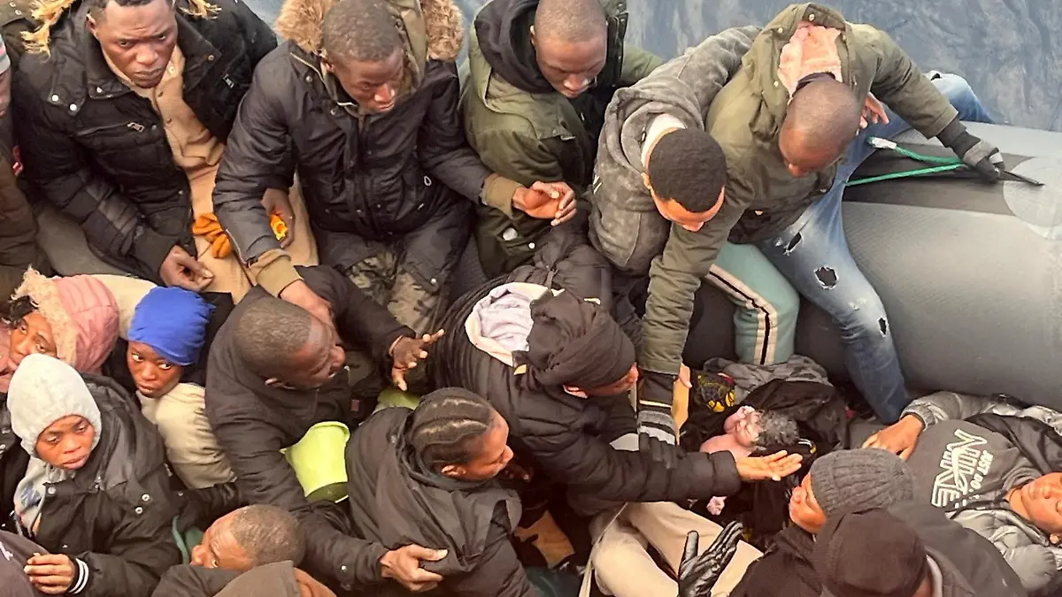 A migrant holds a newborn baby as a woman lies inside a rubber boat with other migrants who were rescued off the island off the Canary Island of Lanzarote in Spain, in this handout picture obtained on January 8, 2025.