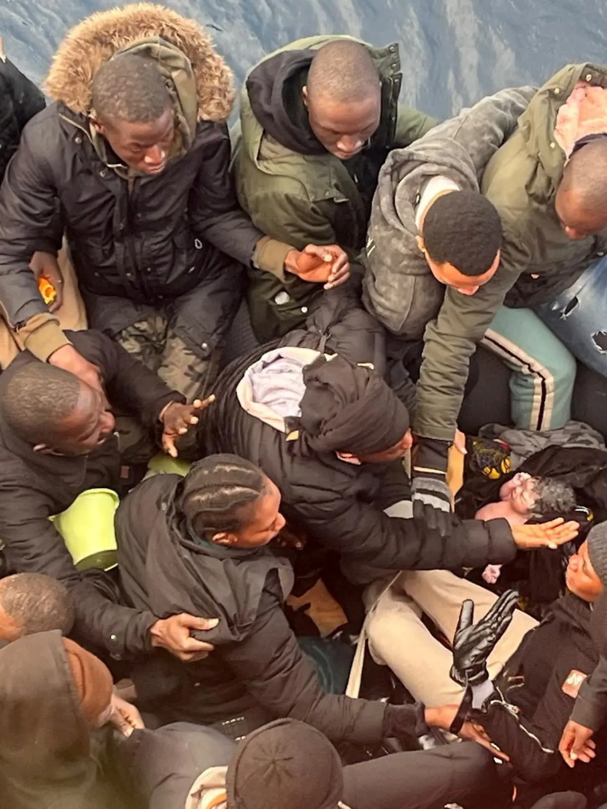 A migrant holds a newborn baby as a woman lies inside a rubber boat with other migrants who were rescued off the island off the Canary Island of Lanzarote in Spain, in this handout picture obtained on January 8, 2025.