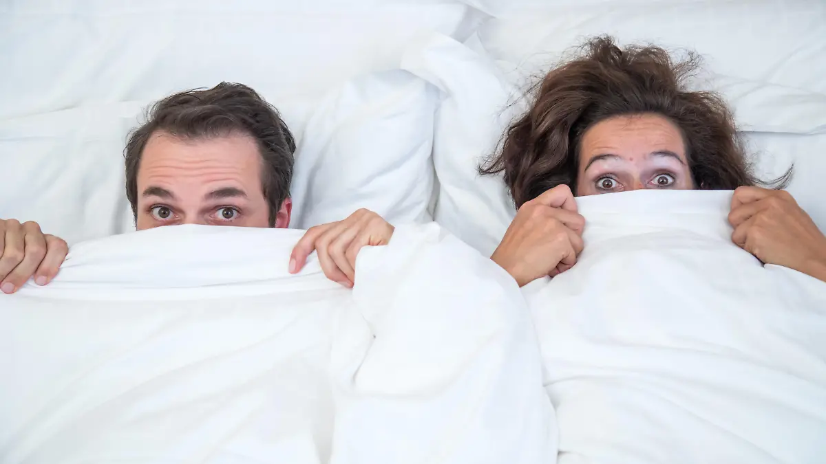 ILLUSTRATION - Ein Paar liegt am 08.09.2017 gemeinsam in einem Bett in einem Hotelzimmer in Hamburg und zieht sich erschrocken die Decke ueber den Kopf (gestellte Szene). Foto: Christin Klose || Modellfreigabe vorhanden