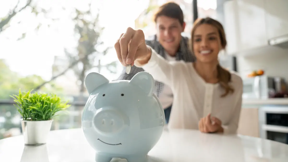 Ein junges Paar spricht über Geld und wirft Bargeld in ihr Sparschwein.