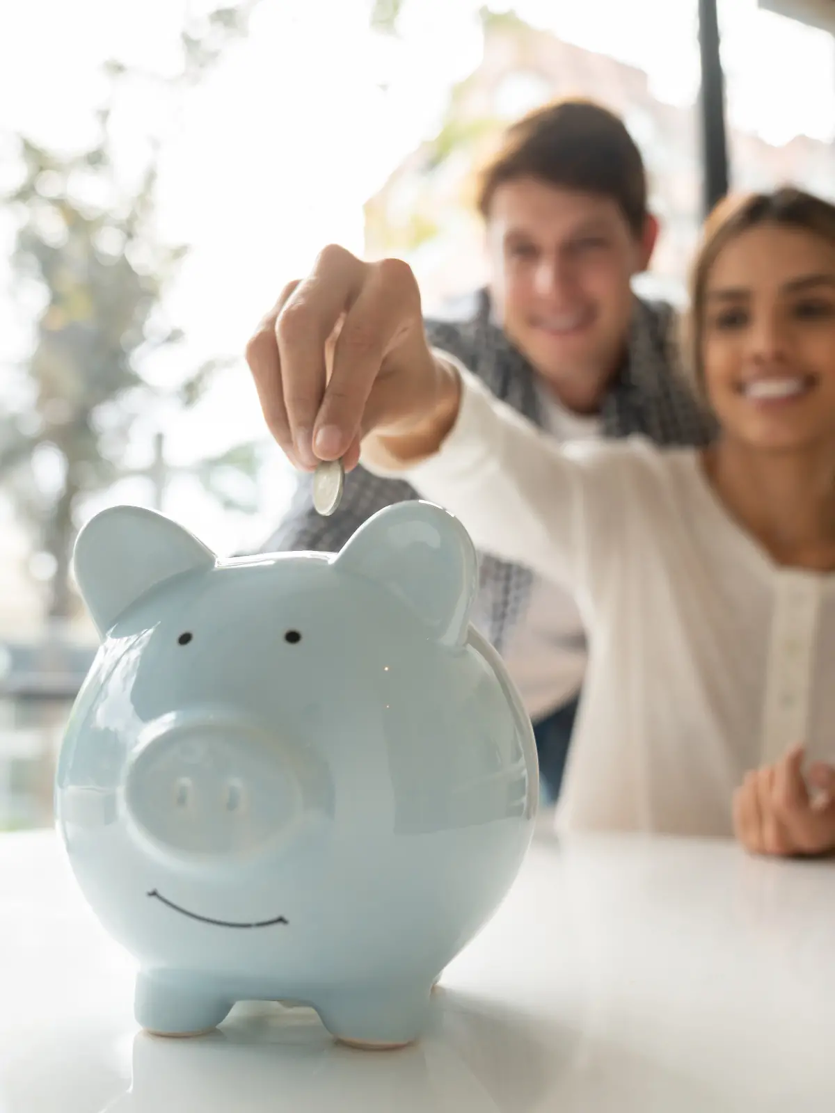 Ein junges Paar spricht über Geld und wirft Bargeld in ihr Sparschwein.