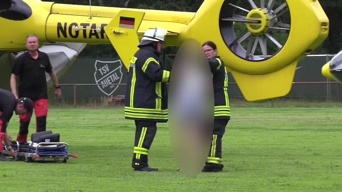 Feuerwehrleute trösten eine Person auf einem Fußballfeld nach dem tödlichen Unfall in Toppenstedt (Landkreis Harburg)