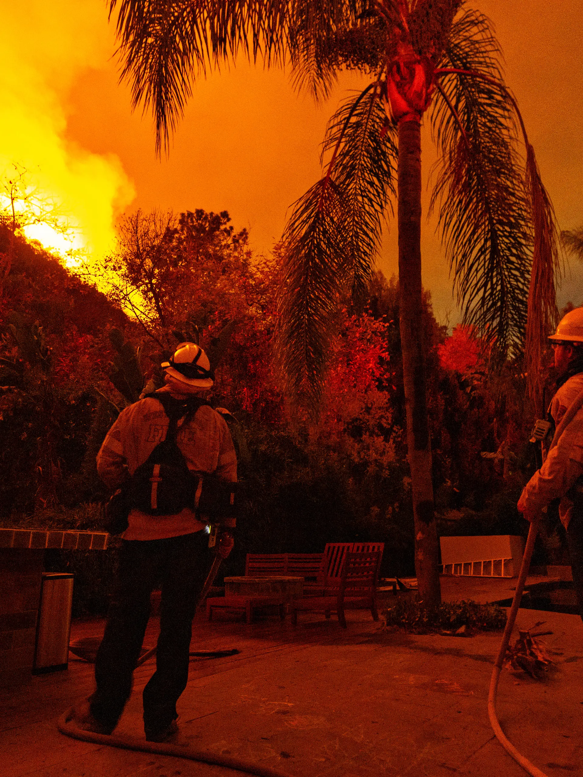 Los Angeles, CA - January 11: Fire fighters stand guard at a home on Mandeville Canyon road as the Palisades fire spreads towards Encino on Saturday, Jan. 11, 2025 in Los Angeles, CA. 