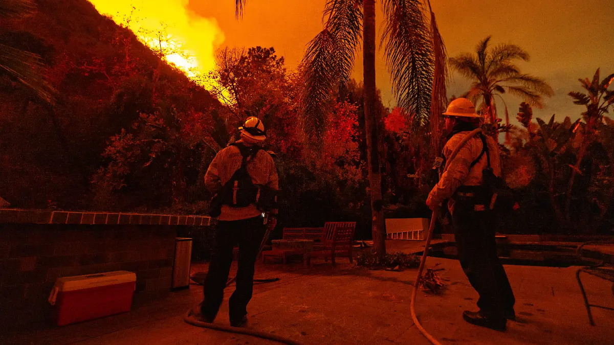Los Angeles, CA - January 11: Fire fighters stand guard at a home on Mandeville Canyon road as the Palisades fire spreads towards Encino on Saturday, Jan. 11, 2025 in Los Angeles, CA. ()