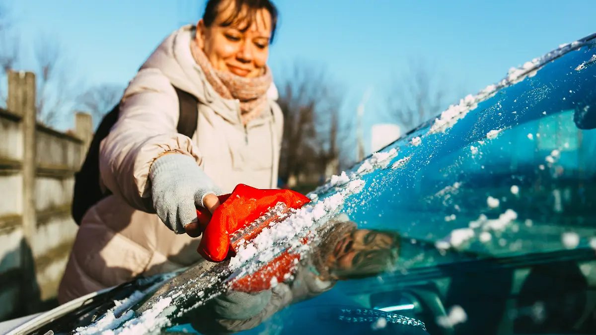 Frau kratzt vereiste Scheibe 