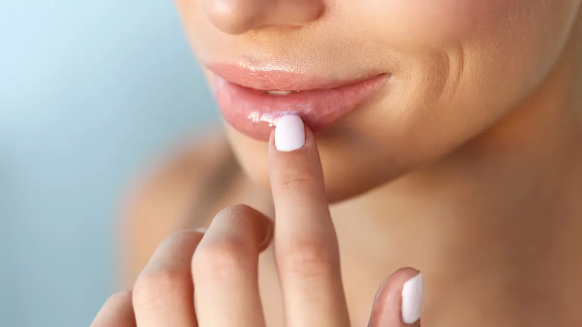Eine Frau trägt Lippenpflege auf ihren Lippen auf.
