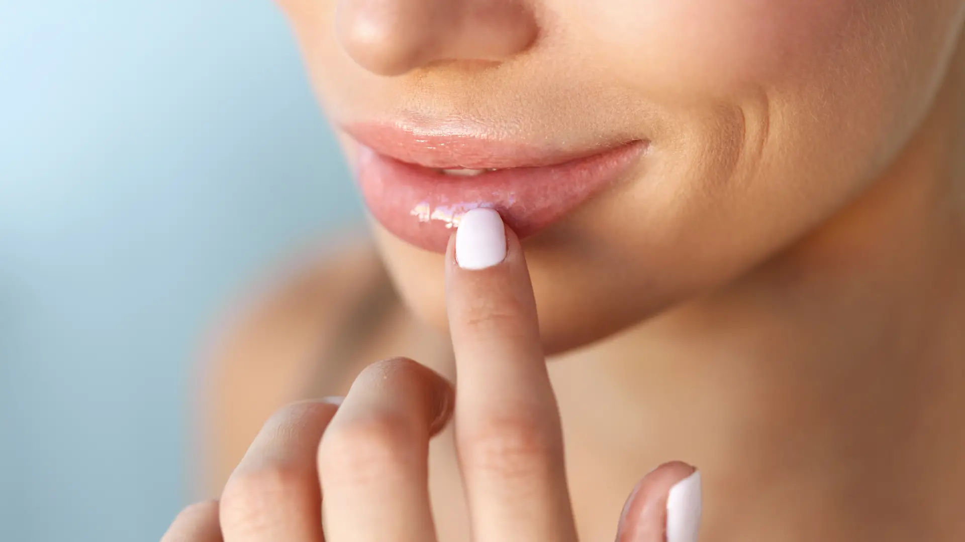 Eine Frau trägt Lippenpflege auf ihren Lippen auf.