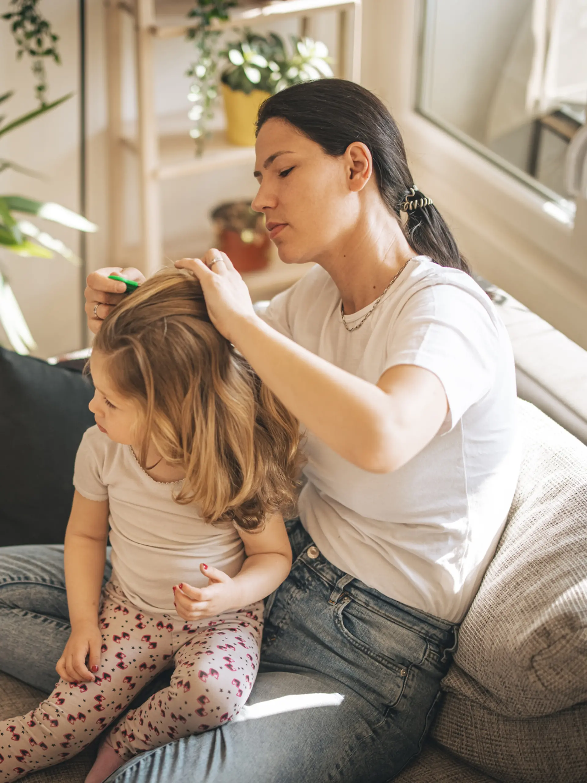 Mutter durchsucht die Haare ihrer Tochter nach Läusen