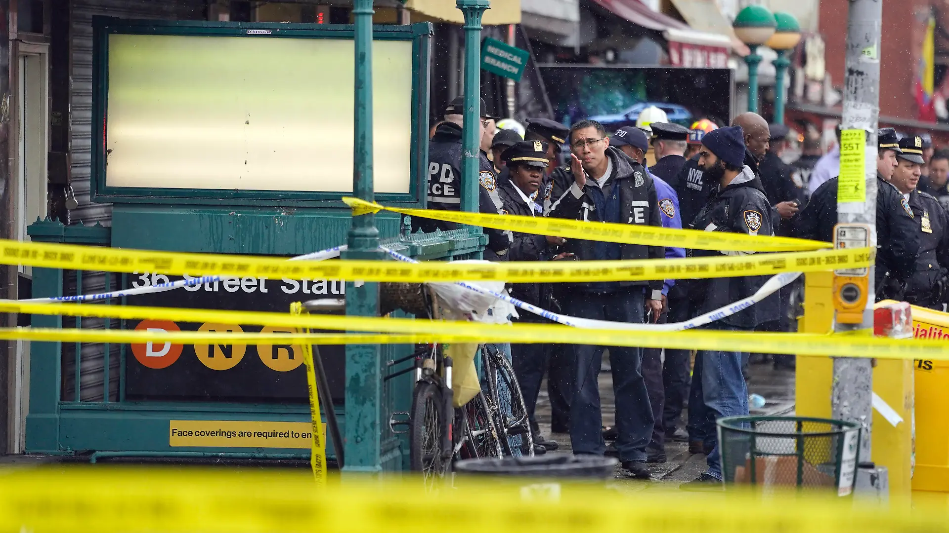 12.04.2022, USA, New York: Mitarbeiter des New York City Police Department versammeln sich am Eingang einer U-Bahn-Station im New Yorker Stadtteil Brooklyn. Bei Schüssen in einer New Yorker U-Bahn-Station sind mehrere Menschen verletzt worden. Foto: John Minchillo/AP/dpa +++ dpa-Bildfunk +++