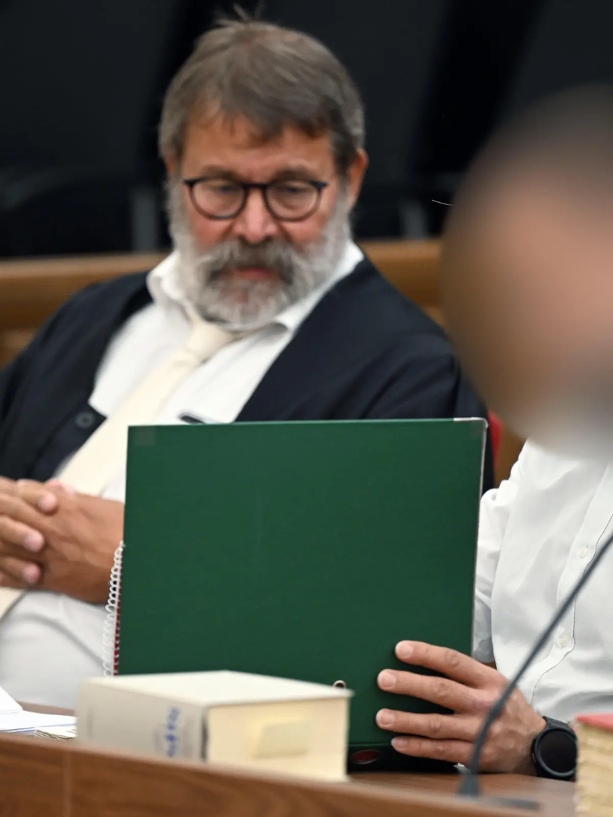 07.07.2023, Nordrhein-Westfalen, Wuppertal: Der Angeklagte (r) sitzt neben seinem Anwalt Jochen Ohliger im Gerichtssaal. Ein 46-Jähriger muss sich wegen Körperverletzung mit Todesfolge vor dem Wuppertaler Landgericht verantworten. Er soll einem 32 Jahre alten Mann Silikonöl in Penis und Hodensack gespritzt haben. Das Opfer wollte so seinen Penis vergrößern lassen. Foto: Federico Gambarini/dpa - ACHTUNG: Person wurde aus rechtlichen Gründen gepixelt +++ dpa-Bildfunk +++