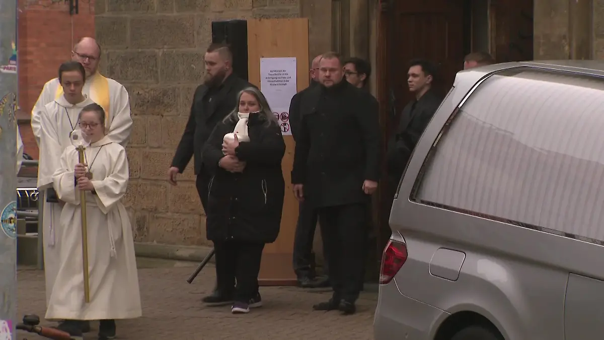 Andrés Mutter (m.) trägt die Urne mit der Asche ihres geliebten Jungen aus der Kirche.
