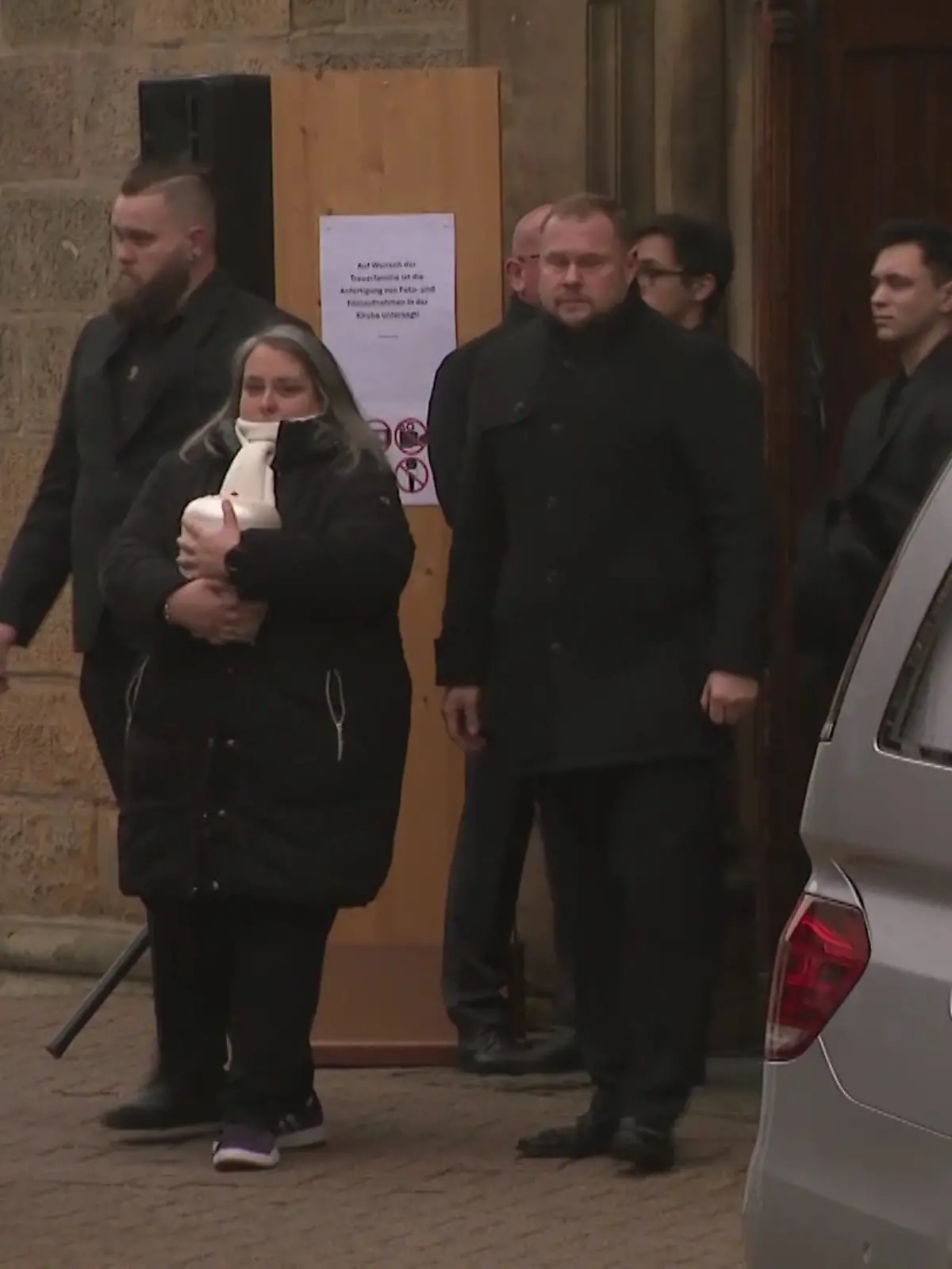 Andrés Mutter (m.) trägt die Urne mit der Asche ihres geliebten Jungen aus der Kirche. 