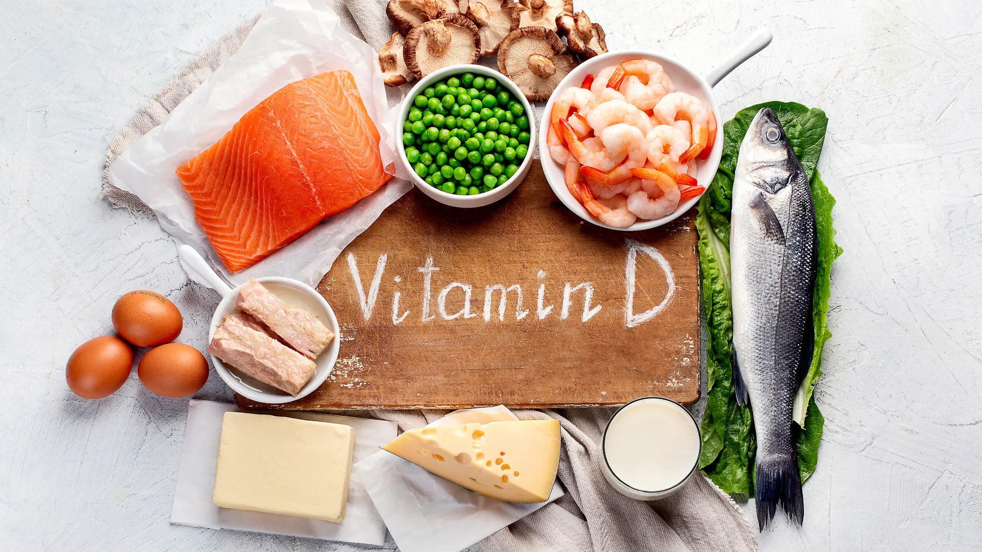 Holzbrett mit der Aufschrift Vitamin D und drum herum verschiedene Lebensmittel