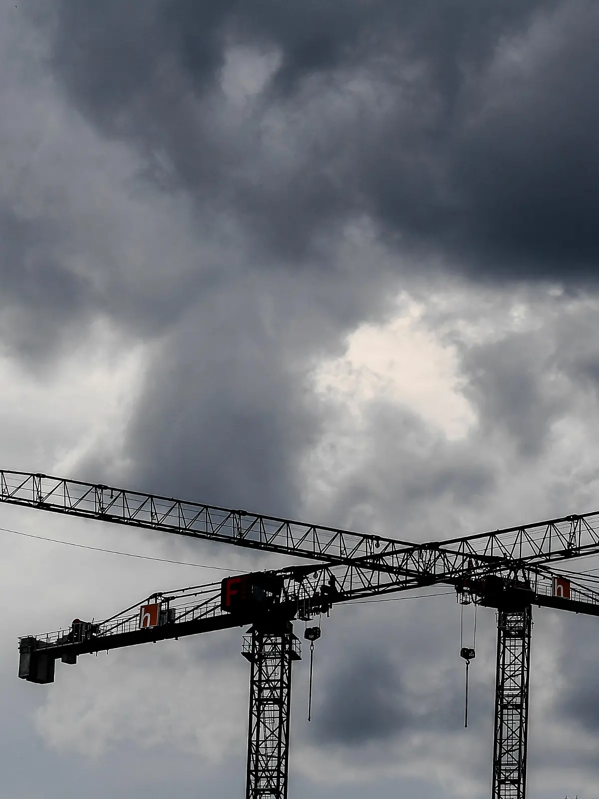 Baukräne vor dunklen Wolken.