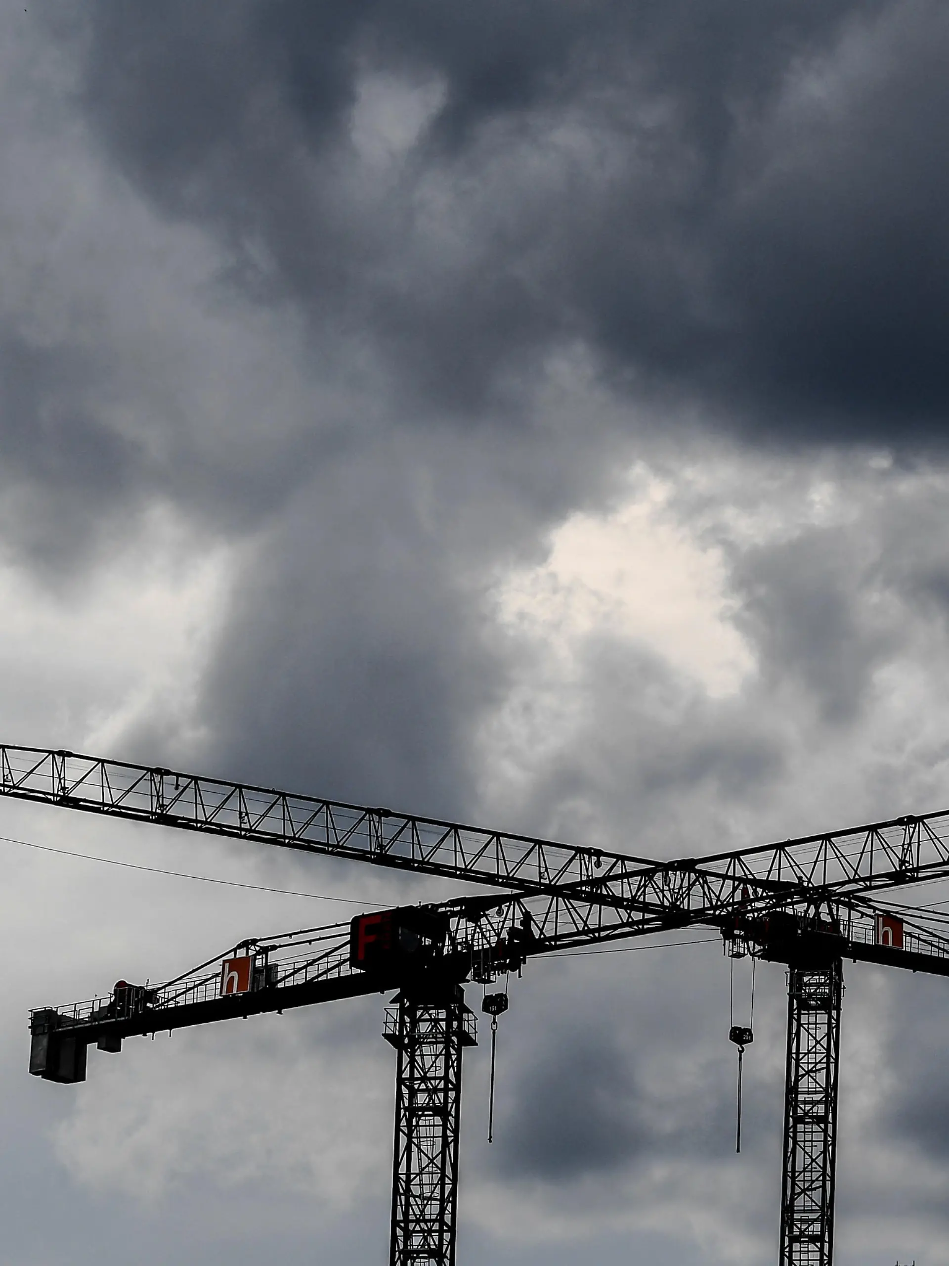 Baukräne vor dunklen Wolken.