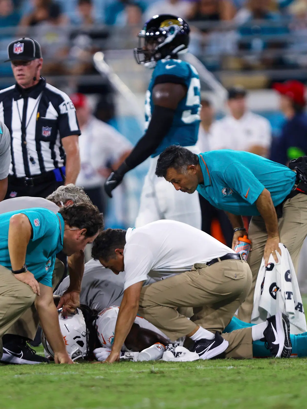 26.08.2023, USA, Jacksonville: American Football: Profiliga NFL, Vorsaison, Jacksonville Jaguars - Miami Dolphins. Wide Receiver Daewood Davis von den Miami Dolphins wird während der zweiten Hälfte des Vorbereitungsspiels untersucht. In der NFL ist knapp zwei Wochen vor dem Saisonstart erneut ein Testspiel nach der Verletzung eines Football-Profis abgebrochen worden. Daewood Davis von den Miami Dolphins blieb nach einem harten Zusammenprall in der Partie gegen die Jacksonville Jaguars am Samstag (Ortszeit) minutenlang mit dem Gesicht auf dem Boden liegen. Foto: Gary McCullough/AP/dpa +++ dpa-Bildfunk +++