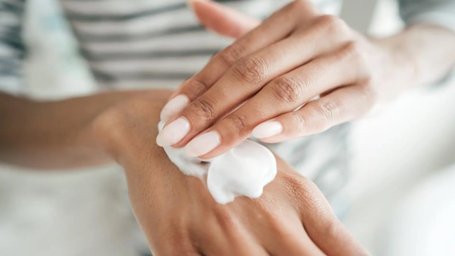 Frau cremt sich mit Handcreme ein, die nicht schmiert.