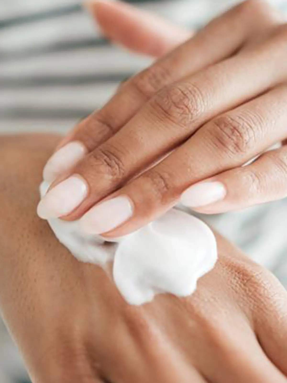 Frau cremt sich mit Handcreme ein, die nicht schmiert.
