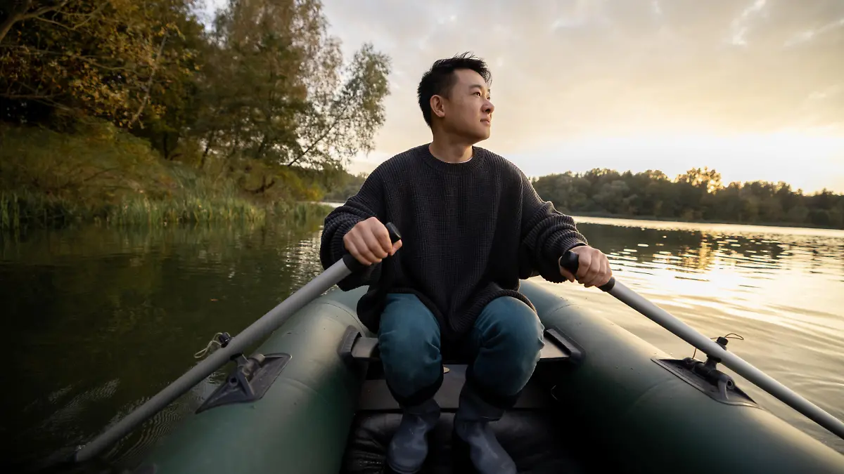 Ein Mann sitzt in einem Schlauchboot auf dem Wasser.