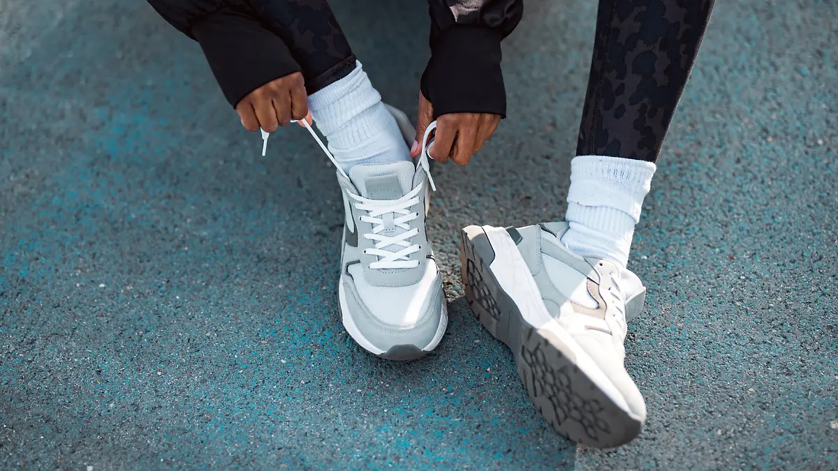 Frau trägt grauen Sneaker-Trend 2025.