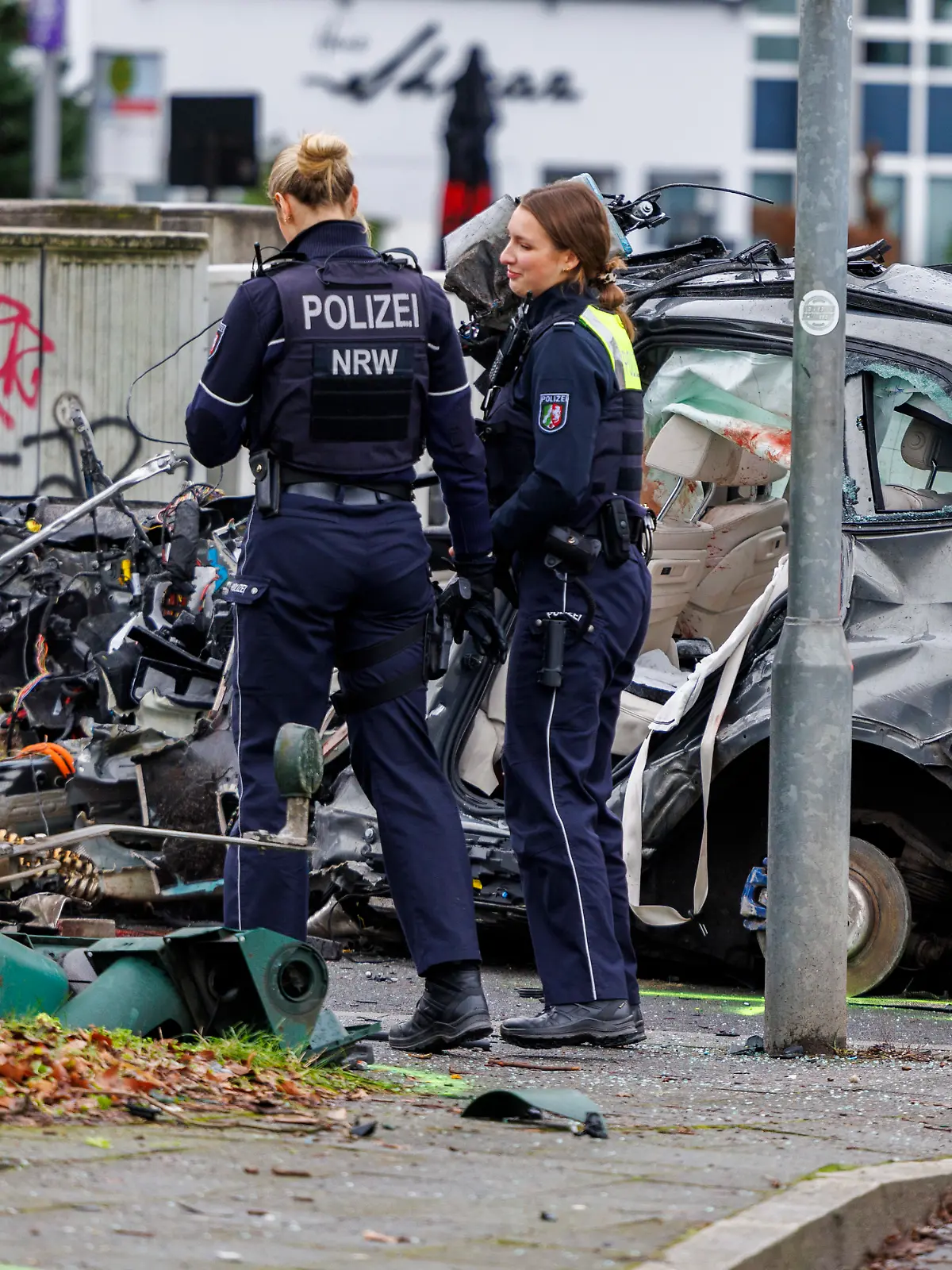 Polizeibeamte stehen am verunfallten Wrack des BMW X5 in Düsseldorf-Golzheim
