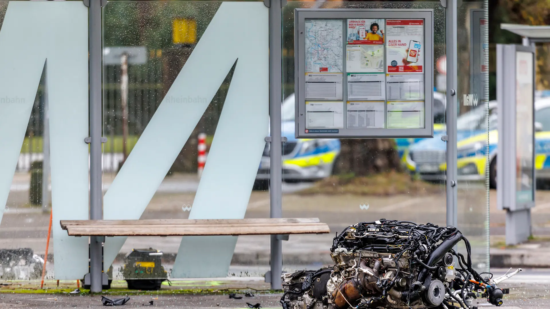 Der herausgerissene Motorblock des BMW liegt auf dem Gehweg vor einer Bushaltestelle in Düsseldorf-Golzheim