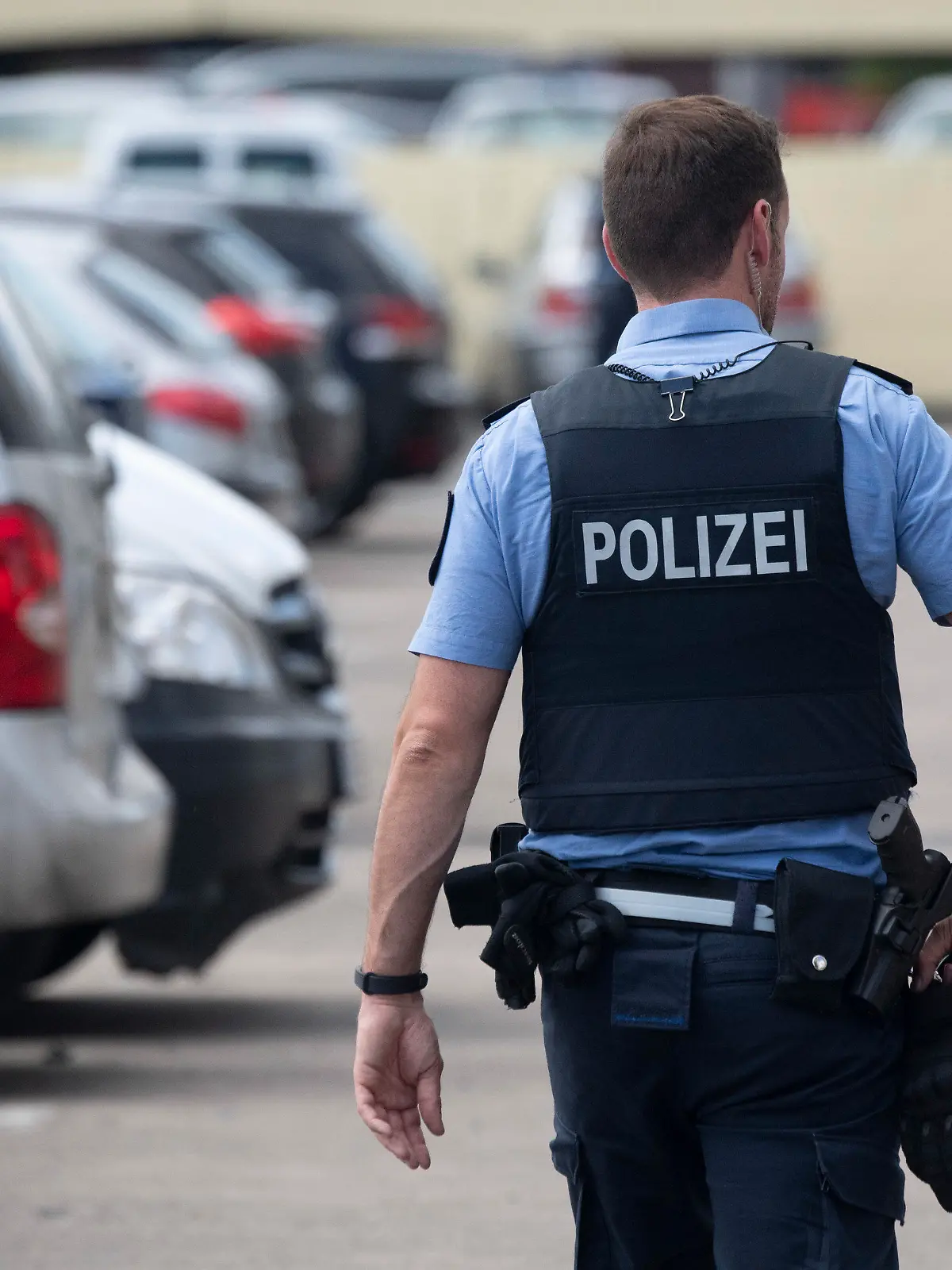 ARCHIV - 29.05.2020, Hessen, Dietzenbach: Ein Polizist geht über den Parkplatz einer Hochhaussiedlung, in der Einsatzkräfte der Polizei und der Feuerwehr mit Steinen beworfen und attackiert worden waren. Nahezu jeder hessische Polizist ist laut Innenministerium schon einmal im Dienst beleidigt worden, mehr als 70 Prozent sind nach eigenen Angaben schon angegriffen worden. (zu dpa «Fast jeder hessische Polizist bereits im Dienst beleidigt») Foto: Boris Roessler/dpa +++ dpa-Bildfunk +++