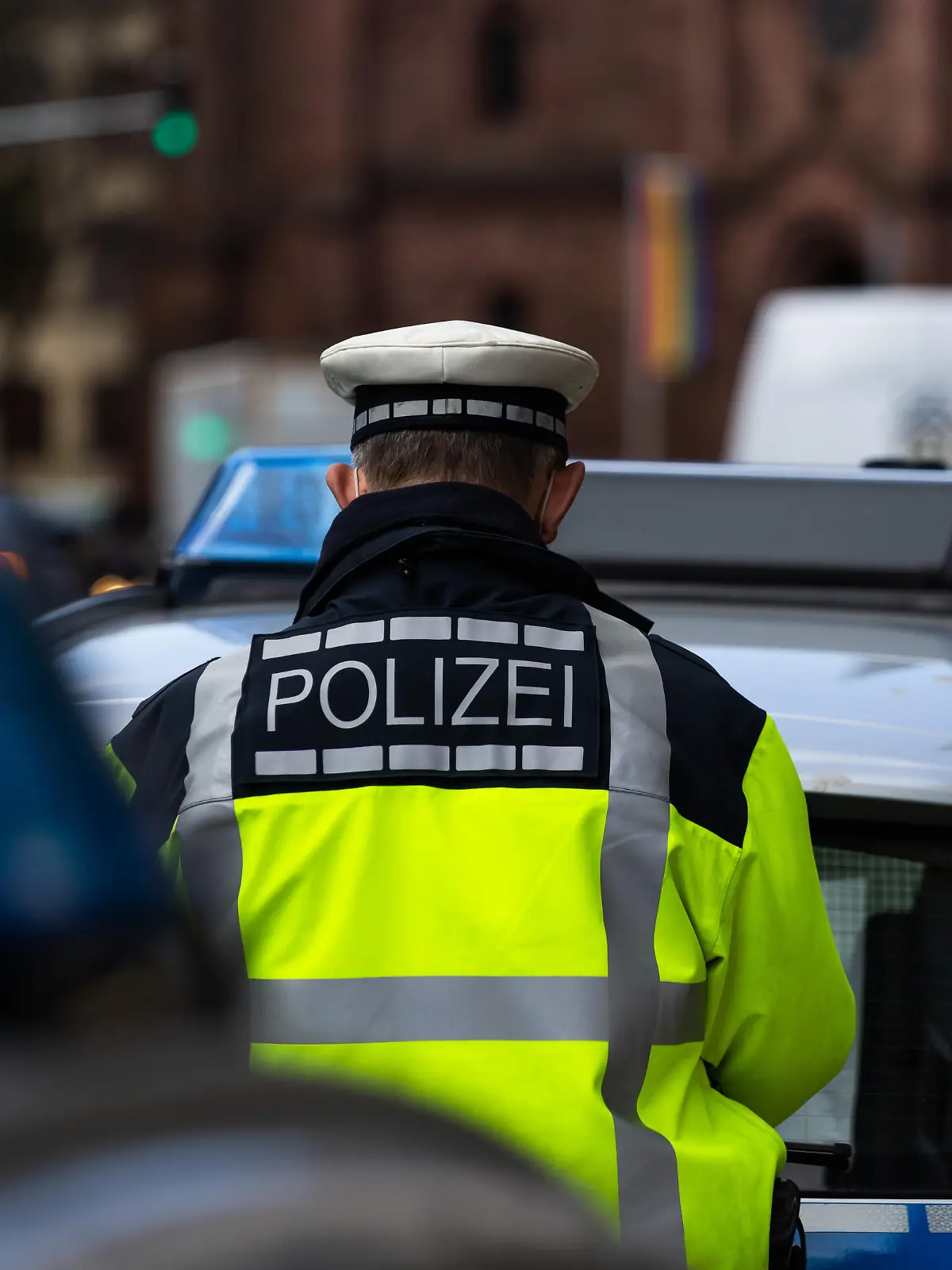 Ein Polizeibeamter steht zwischen zwei Einsatzfahrzeugen der Polizei.