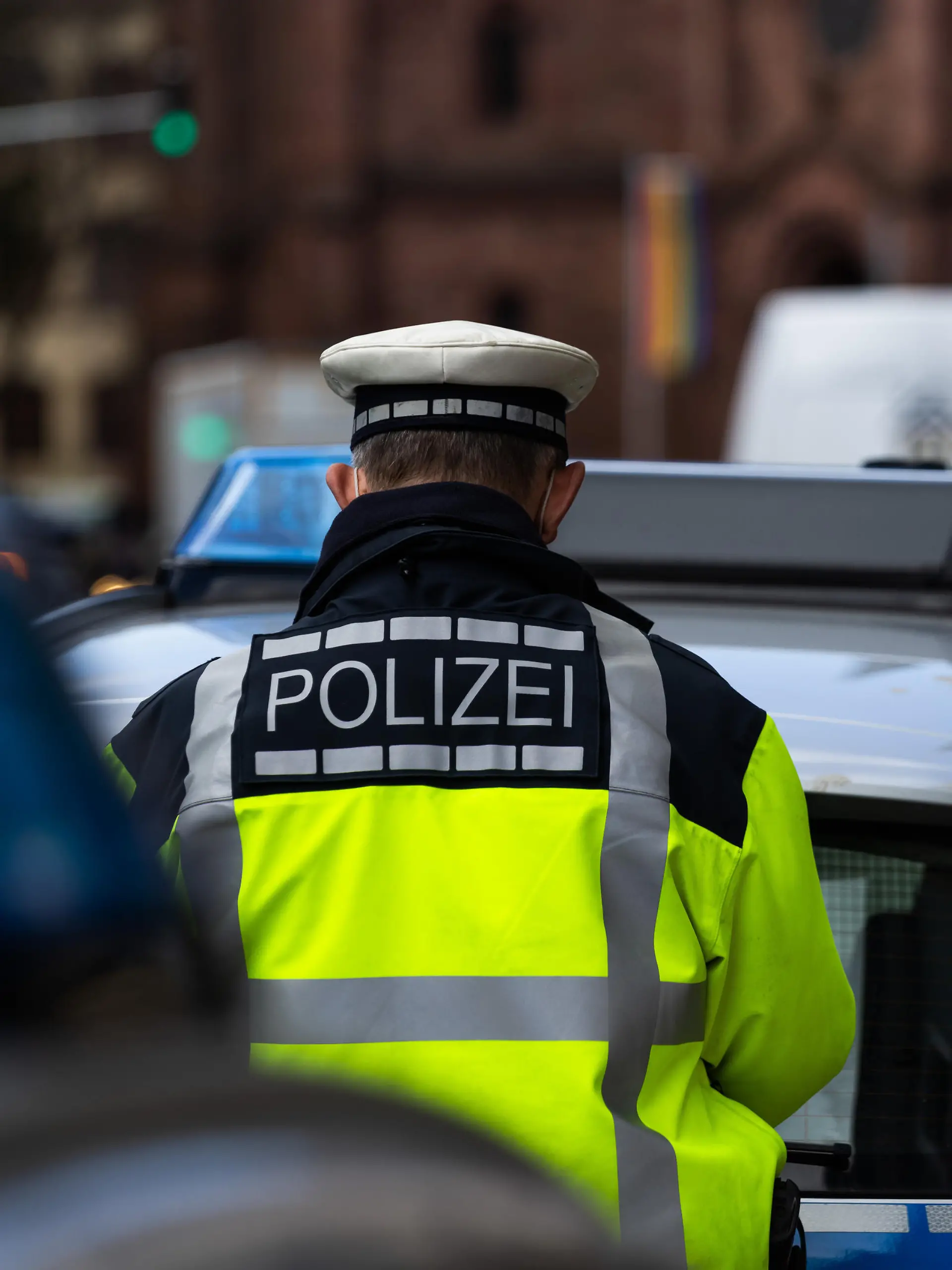 Ein Polizeibeamter steht zwischen zwei Einsatzfahrzeugen der Polizei.