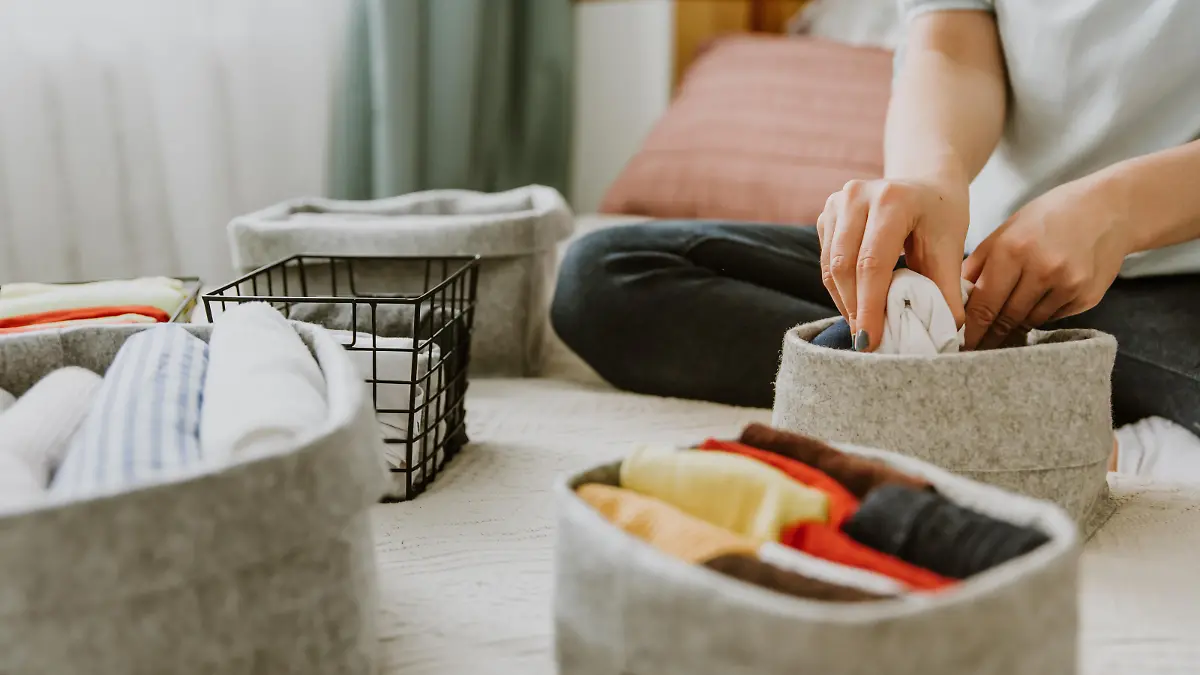 Woman organizing clothes in wardrobe, putting shirts in boxes. Concept of order, minimalist closet, japanese t-shirt folding system and clothes storage