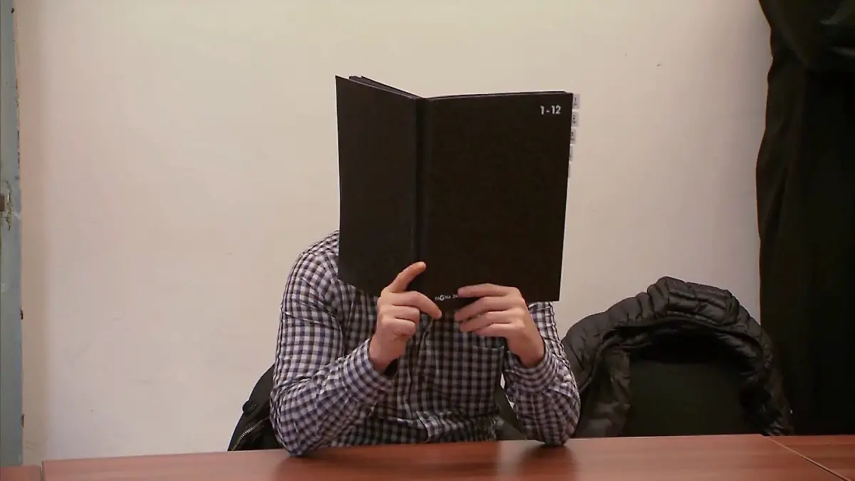 Beim Prozessauftakt versteckt der Angeklagte sein Gesicht hinter einer Aktenmappe. 
