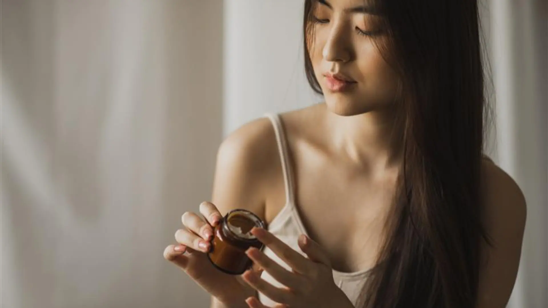 Koreanische Frau trägt Creme auf.