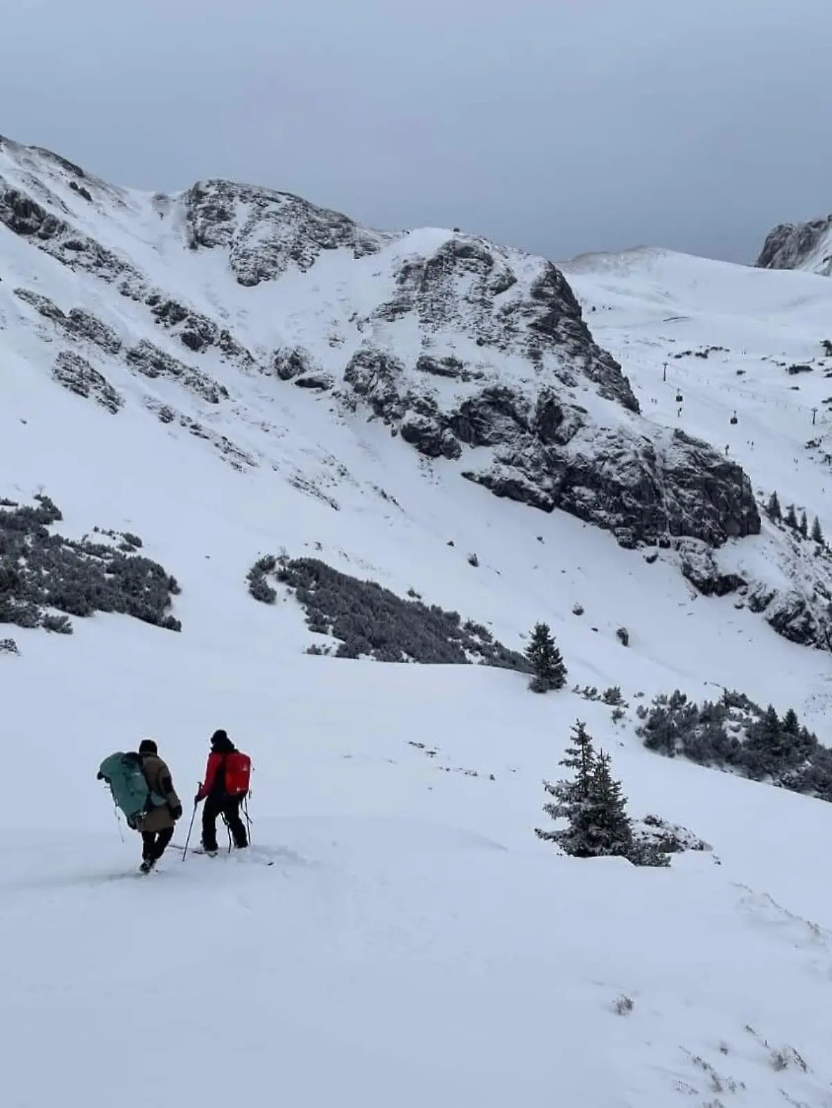 Zwei Menschen aus Skier wandern einen schneebedeckten Berg hoch.