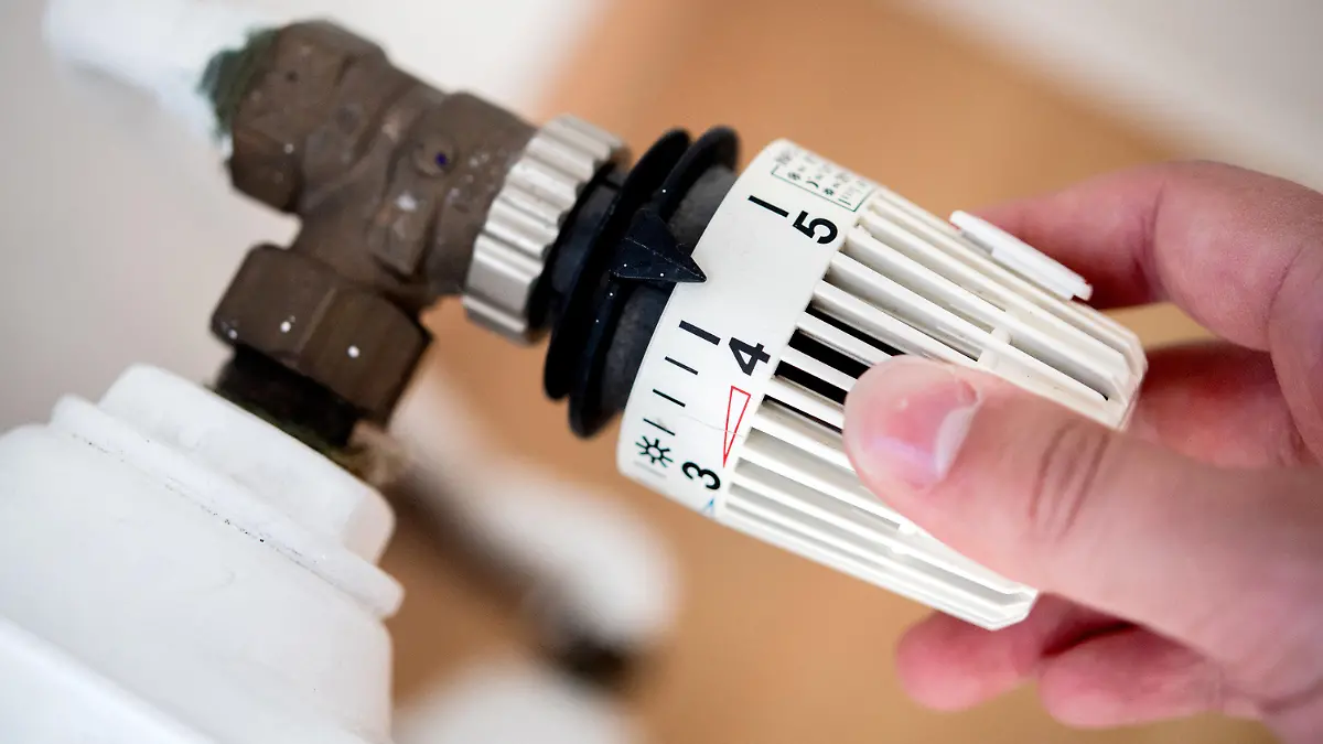 ARCHIV - 04.10.2021, Niedersachsen, Hannover: ILLUSTRATION - Ein Mann dreht in einer Wohnung am Thermostat einer Heizung. (zu dpa: «Mieter sollen Klimaabgabe beim Heizen nicht mehr alleine zahlen») Foto: Hauke-Christian Dittrich/dpa +++ dpa-Bildfunk +++